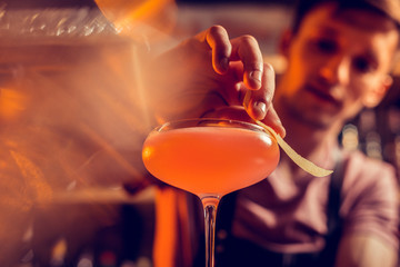Barman perfecting cocktail for his client while working at night