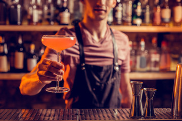 Barman wearing apron showing nice alcohol cocktail