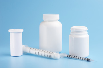 Syringes and white bottles with pills on a blue background.
