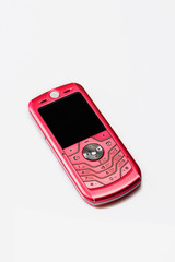 Old, pink mobile phone on white background. Close up. Selective focus.