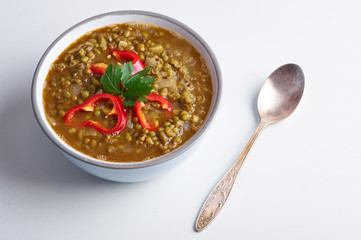 Mung Dhal with red pepper slices isolated at white. Moong Dal - Indian Cuisine curry. Vegetarian dish with mung beans, zira cumin, coriander and chili