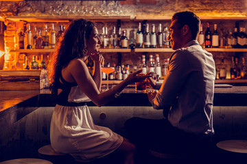 Young lovely couple sitting at the bar stand and talking - obrazy, fototapety, plakaty
