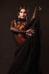 Beautiful belly dancer perfoming exotic dance in red flutter dress