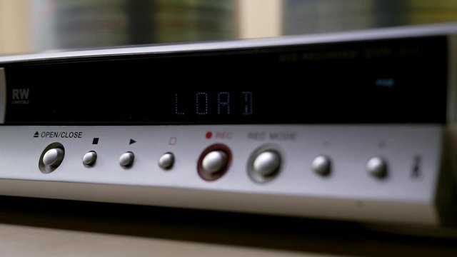 Finger presses play button on electronic scoreboard screen on dvd player at home