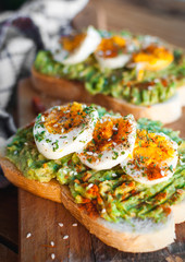 Close-up of avocado and egg toast with herbs and seasonings, on cutting board