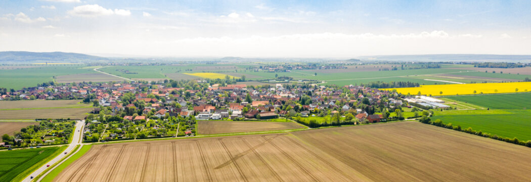 Composite panorama of aerial photos of a village in northern Germany with houses between a cultural landscape with fields and meadows, drone shot
