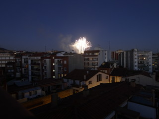 Vista nocturna de un barrio cualquiera de una ciudad cualquiera con fuegos artificiales al fondo