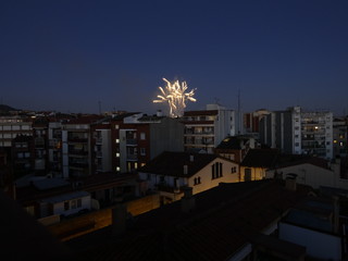 Vista nocturna de un barrio cualquiera de una ciudad cualquiera con fuegos artificiales al fondo