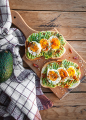 Avocado and egg toast with herbs and seasonings, on cutting board, top view
