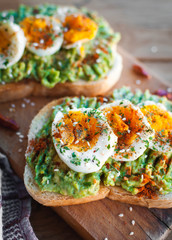 Close-up of avocado and egg toast with herbs and seasonings, on cutting board