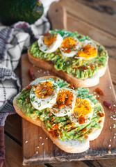 Close-up of avocado and egg toast with herbs and seasonings, on cutting board
