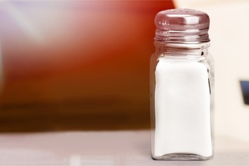 White glass salt shaker on white desk