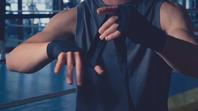 Close-up boxer wrapping bandages on his hand before boxing exercise. Muay thai fighter or kickboxer