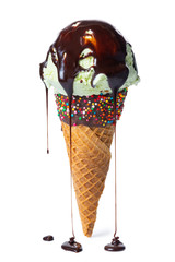 wafer cone decorated colorful sprinkles and chocolate icing with green scoop of ice cream and current glaze isolated on white background
