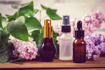 Obraz na płótnie Canvas scent sprayers and essential oil bottles with lilac blossoms