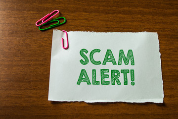 Word writing text Scam Alert. Business photo showcasing fraudulently obtain money from victim by persuading him Close up blank stationary paper hold three colored clips lying wooden table
