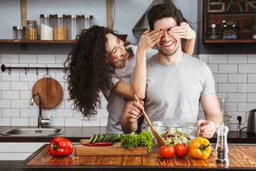 Excited cheerful young couple cooking healthy salad