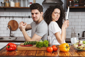 Excited cheerful young couple cooking healthy salad