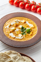 Shahi paneer Indian vegetarian masala gravy meal with vegetables, white sauce and butter paneer cottage cheese spicy food vegan north India dish served with cherry tomatoes on white wooden background