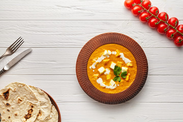 Shahi paneer Indian rustic vegetarian masala gravy meal with vegetables and butter paneer cottage cheese vegan north India dish served with cherry tomatoes and chapati nan on white wooden background