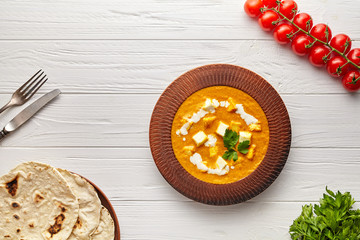 Shahi paneer traditional Indian vegetarian rustic masala gravy meal with vegetables, white sauce spicy food vegan north India dish served with cherry tomatoes, nan and parsley on white background