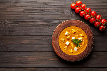 Shahi paneer traditional Indian vegetarian tomato gravy meal with vegetables and butter paneer cottage cheese spicy food north India dish served with tomatoes on dark wooden background