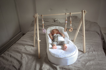 newborn sleeps on special device with wood toys