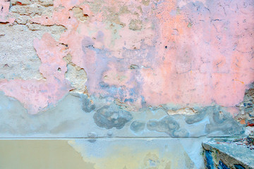 Old weathered painted wall background texture. White grey pink dirty peeled plaster wall with falling off flakes of paint