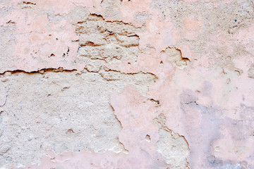 Old weathered painted wall background texture. White grey pink dirty peeled plaster wall with falling off flakes of paint