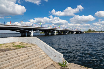 Road bridge connecting the two banks of the river in the city. Clear day, blue sky with white clouds.