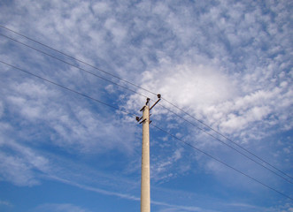 Electric concrete pole with wires. Background sky with light clouds. Metal constructions. Ceramic...