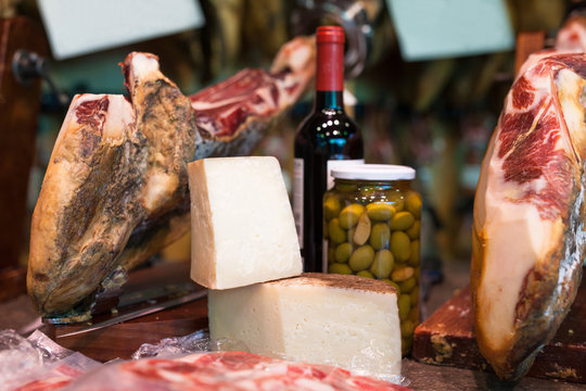 Still life of spanish pork jammon on holder, bottles of wine cheese and olives