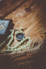 Traditional muslim prayer set bundle. Praying carpet, rosary beads, little version of the Holy Quran and qibla compass on wooden background. Free Space