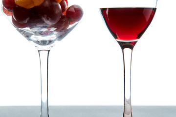 Crystal glasses with red grape and tasty wine on white background