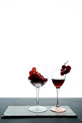 Crystal glasses with red grape and tasty wine on white background