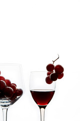 Crystal glasses with red grape and tasty wine on white background
