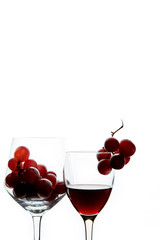 Crystal glasses with red grape and tasty wine on white background
