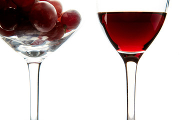 Crystal glasses with red grape and tasty wine on white background