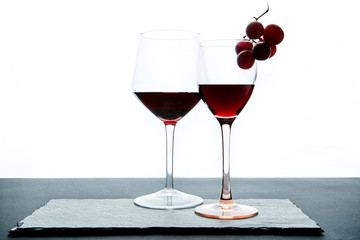 Composition of glasses with ripe grape and red wine served on slate board
