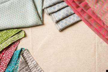  A variety of colourful fabrics folded and layed out over a canvas table with copy space for text.