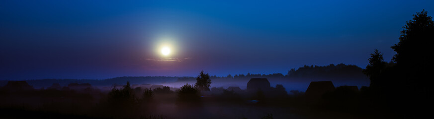 Fototapeta na wymiar Night fog under the village at the blue moonlight