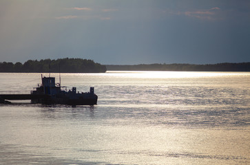 Ferry pier on the river in beams setting the sun