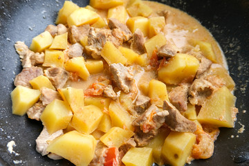 Potatoes with pork stewed in a pan. Vegetables and meat for dinner.