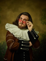 Young man as a medieval knight in sunglasses on dark studio background. Portrait in low key of male...