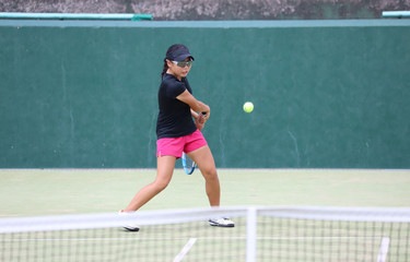 バックハンドを打つジュニアテニスプレイヤー