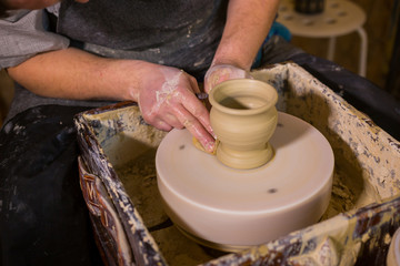 Professional potter shaping mug with special tool in pottery workshop