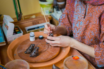 Fototapeta premium Professional woman potter painting ceramic souvenir penny whistle in pottery