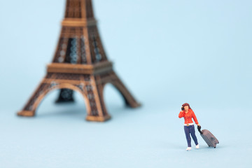 miniature Eiffel tower and women tourist on blue background