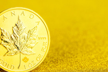 silver and golden canadian maple leaf one ounce coins on golden background