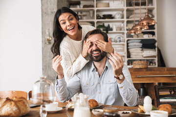 Fototapeta na wymiar Portrait of pretty couple having fun together while having breakfast in kitchen at home